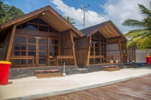 un bâtiment en bois avec des bancs devant lui dans l'établissement Teras Pahawang, à Sukojayo