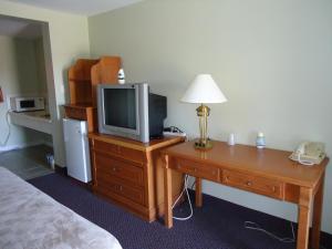 um quarto de hotel com uma televisão e uma secretária com uma cama em Westmount Motel em Woodstock