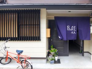 una bicicleta estacionada frente a un edificio con una pancarta en Guesthouse Bell Fushimi, en Kioto