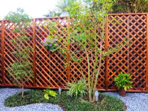 a wooden fence with some trees and plants at Guesthouse Bell Fushimi in Kyoto