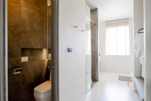 La salle de bains est pourvue de toilettes et d'une porte de douche en verre. dans l'établissement Doowall Hotel, à Chiang Rai