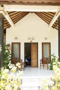a patio with two chairs and a wooden door at Coconut Village Guest House Lembongan RedPartner in Nusa Lembongan
