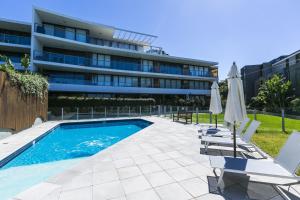 a swimming pool with chairs and umbrellas in front of a building at Lorne Chalet Apartment 38 in Lorne