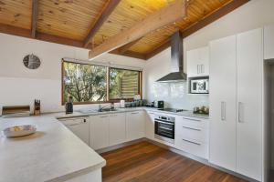 a kitchen with white cabinets and a wooden ceiling at Apollo Bay People N Paws in Apollo Bay