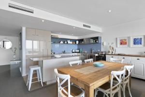 Una cocina con una mesa de madera y gabinetes blancos. en Lorne Chalet Apartment 42, en Lorne