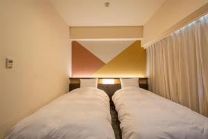 two beds in a small room with a window at Hotel Kanazawa in Kanazawa