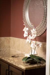 un vase de fleurs blanches sur un comptoir devant un miroir dans l'établissement Monument Inn & Suites, à Gering