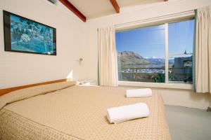 a bedroom with a bed and a large window at Panorama Court in Wanaka