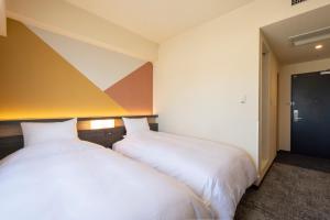 two beds sitting next to each other in a room at Hotel Kanazawa in Kanazawa