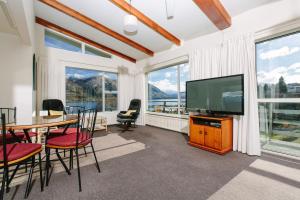 a living room with a television and a table and chairs at Panorama Court in Wanaka