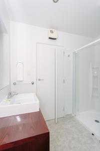 ein weißes Bad mit einem Waschbecken und einer Dusche in der Unterkunft Panorama Court in Wanaka