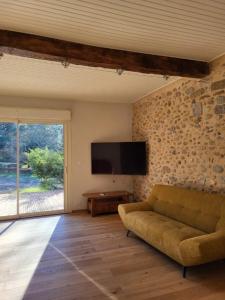 sala de estar con sofá y TV de pantalla plana en Gîte PRAT NAOU - PYRENNEES ARIEGEOISES, en Taurignan-Vieux