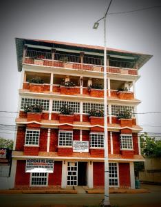 a red building with white windows and plants on it at El Rincón del Ángel Tuxpan in Tuxpan de Rodríguez Cano