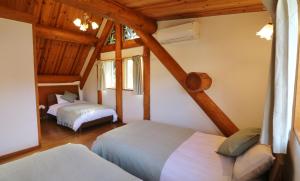 1 dormitorio con 2 camas en una habitación con techos de madera en ログキャビン伊豆高原, en Futo