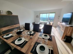 una sala da pranzo con tavolo e sedie in legno di T3 avec magnifique vue montagne, 3 étoiles, piscine et parking, clim a Mougins