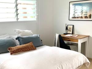 1 dormitorio con cama blanca y escritorio en THE BEACH HAVENS - Haven Oceana, en Emerald Beach