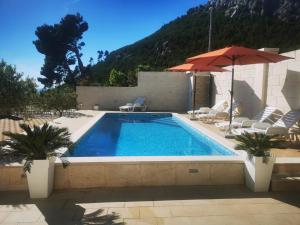 a swimming pool with an umbrella and some chairs at Apartment Marco in Makarska