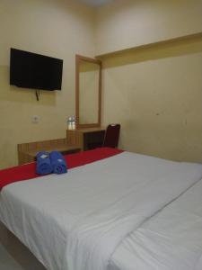 a bedroom with a large white bed with a television on the wall at Hotel Mayang Sari 1 in Jambi