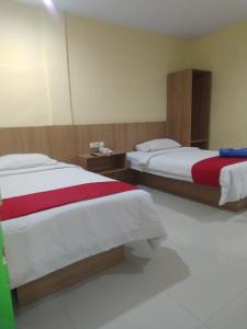 a hotel room with two beds with red and white sheets at Hotel Mayang Sari 1 in Jambi