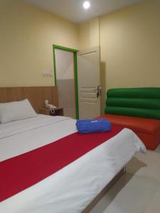 a bedroom with a bed with red and green sheets at Hotel Mayang Sari 1 in Jambi