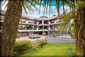 un gran edificio de apartamentos con un patio con palmeras en Alevic Hotel Sirmione en Sirmione