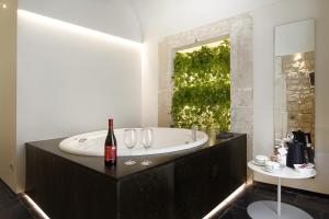 bagno con vasca, bottiglia di vino e bicchieri da vino di Iblaresort Boutique Hotel a Ragusa