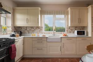 a kitchen with white cabinets and a window at Chase Lodge, Kenilworth, Family Sized Cottage With free Wifi in Kenilworth
