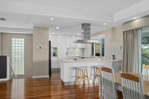 a kitchen and dining room with white cabinets and wood floors at Wauwa-ana - Moana - C21 SouthCoast Holidays in Moana