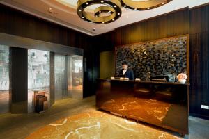 uma mulher parada num balcão no átrio de um hotel em Hotel One Eighteen em Hong Kong