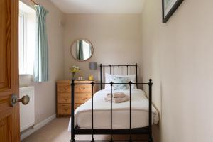 a bedroom with a black bed frame and a mirror at Chase Lodge, Kenilworth, Family Sized Cottage With free Wifi in Kenilworth