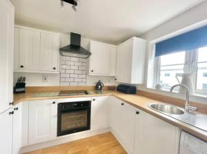 a white kitchen with white cabinets and a sink at Lovely 2-Bedroom Bristol Apartment. FREE PARKING. in Bristol