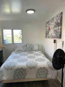 a bedroom with a bed with a comforter and two windows at Tavares house in Waialua