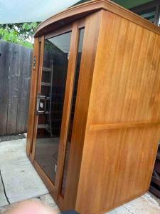 a wooden enclosure with a glass door on a patio at Tavares house in Waialua