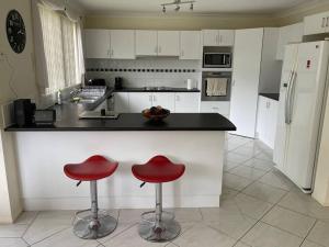 una cocina con dos taburetes rojos en un mostrador en Beautiful 5 bedroom house in Jervis Bay en Sanctuary Point
