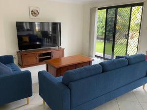 a living room with two blue couches and a tv at Beautiful 5 bedroom house in Jervis Bay in Sanctuary Point