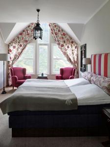 a bedroom with a large bed and two pink chairs at Hotel Union Geiranger Bad & Spa in Geiranger