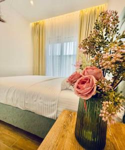 1 dormitorio con 1 cama y un jarrón con flores sobre una mesa en Garden Villas, en Donji Štoj