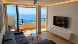 ein Wohnzimmer mit einem Sofa und einem Flachbild-TV in der Unterkunft BEACHFRONT -- NEW LUXURY Apartment -- 1ª Linea Playa -- Fuengirola CITY CENTER -- Private PARKING -- Panoramic Sea Views -- in Fuengirola