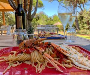 une assiette de pâtes aux crevettes sur une table avec un verre de vin dans l'établissement Residence Pineta, à Albinia
