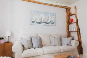 a white couch in a living room with sailboats on the wall at Ferienhaus Lüttes Landhuus in Oersberg