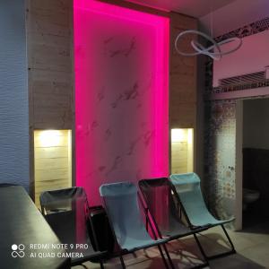 Casa Steluta في سيغيسوارا: مجموعة من الكراسي في غرفة ذات إضاءة وردية