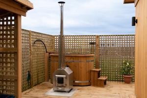 a outdoor grill on a deck with a fence at The Paddock- Loch Lomond and Trossachs in Gartmore