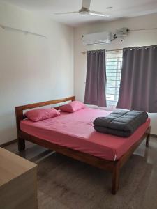 um quarto com uma cama grande e lençóis cor-de-rosa em Castle BGR em Bangalore