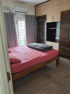 a bedroom with a bed with red sheets and cabinets at Castle Bannerghatta Road in Bengaluru