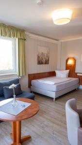 a hotel room with a large bed and a table at Hotel Am Uenglinger Tor in Stendal