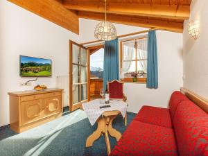 a living room with a red couch and a table at Gästehaus beim Foidlmoar Familie Höflinger in Reit im Winkl