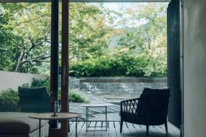 een patio met 2 stoelen, een tafel en een raam bij MUNI KYOTO by Onko Chishin in Kyoto