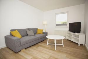 un soggiorno con divano, TV e tavolo di Ferienwohnung mit Terrasse in ruhiger Lage - Haus Südperd FeWo Strandwinde a Thiessow