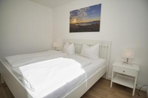 Dormitorio blanco con cama blanca y mesita de noche en Ferienwohnung mit Terrasse in ruhiger Lage - Haus Südperd FeWo Strandwinde en Thiessow