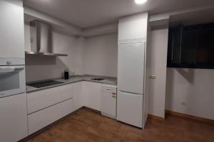 a white kitchen with white cabinets and appliances at Casas da Bríxida. Apartamento accesibel in Cangas de Morrazo